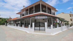 A two-story building with a balcony, a sign for rent, and a gated entrance. - Gregory Apartments  (Kassandra)
