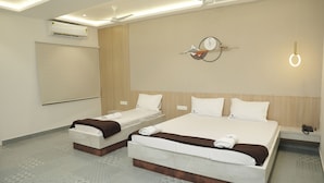 A hotel room with two beds, a ceiling fan, an air conditioner, a clock, and a bedside table with a phone. - Hotel Golden Sea (Kanyakumari)