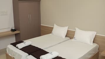 A modern hotel room with a large bed, a wardrobe, and a ceiling fan.