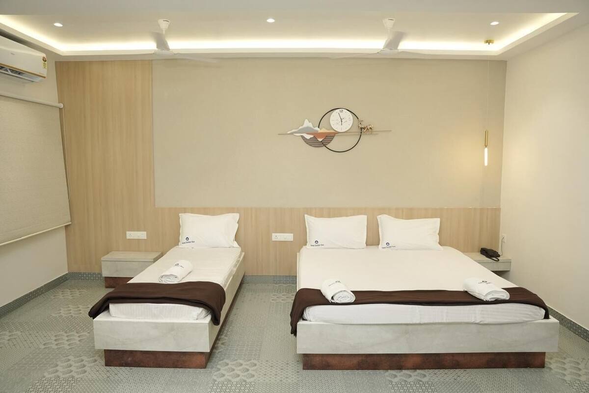 A hotel room with two beds, a wall clock, and a ceiling fan.