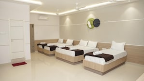 A hotel room with three single beds, a white door, and a red rug. - Hotel Golden Sea (Kanyakumari)