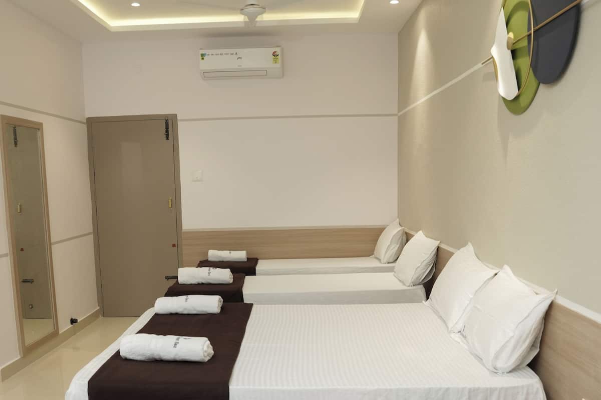 A hotel room with four beds, a ceiling fan, recessed lighting, an air conditioning unit, and a mirror on the left wall.