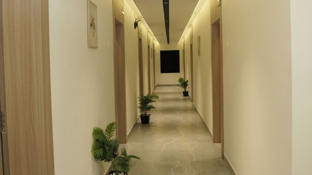A long, well-lit hallway with wooden doors and potted plants. - Hotel Golden Sea (Kanyakumari)