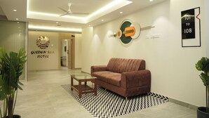 A modern lobby with a brown sofa, a glass coffee table, and a geometric patterned rug. - Hotel Golden Sea (Kanyakumari)