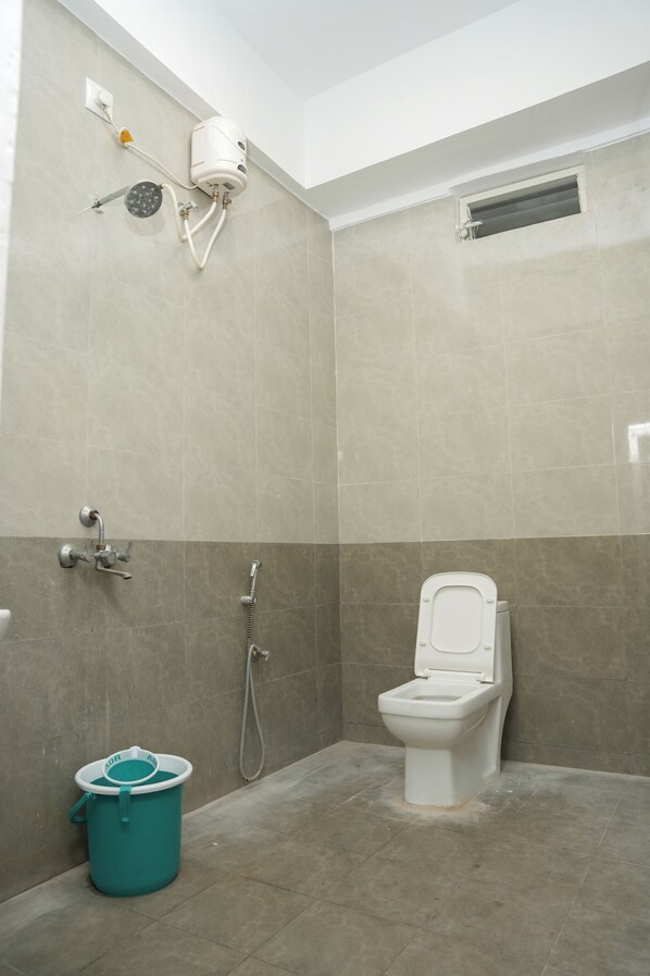 A bathroom with a toilet, shower, and a bucket.