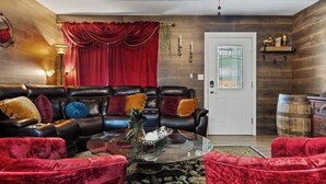 Una sala de estar con sofá de cuero, sillas de terciopelo rojo, una mesa de centro de cristal y una pared de madera.