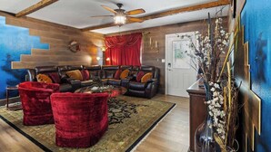 Una sala de estar con un sofá modular, sillones de terciopelo rojo, una mesa de centro y un jarrón decorativo.