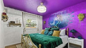 Un dormitorio con cama, mesita de noche, estante en la pared y ventana.