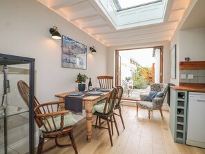 A dining area with a wooden table, chairs, and a cityscape painting. - The Old Post Office (Littlehampton)