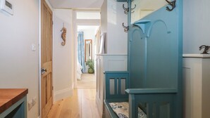 Un pasillo con suelo de madera, un banco azul y una puerta de madera.