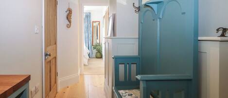 A hallway with wooden flooring, a blue bench, and a wooden door.