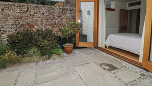 Un dormitorio con puerta de madera, cama y pared de piedra visible desde el exterior.