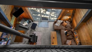A cozy room with a sofa, a coffee table, and a TV. There is a sliding glass door leading to a balcony.