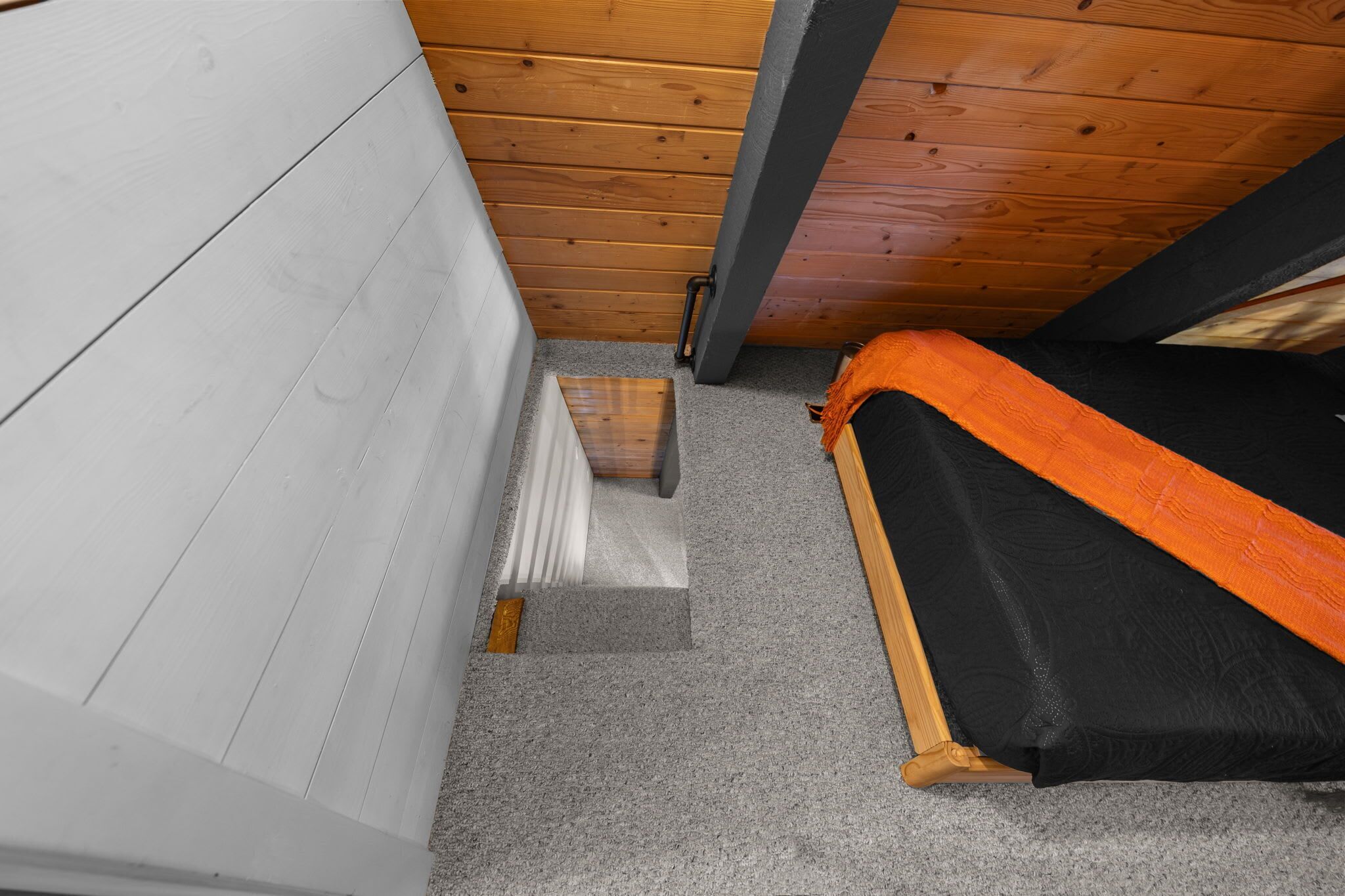 Ein Schlafzimmer mit einem Bett, Holzboden und einer weißen Wand.