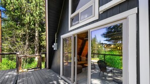 A wooden deck with a sliding glass door leading to an outdoor seating area with a sofa and chairs.