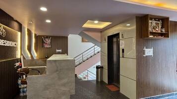 Eine moderne Hotelhalle mit Empfangstresen, einer Treppe und einem Schild mit der Aufschrift 'Café'.