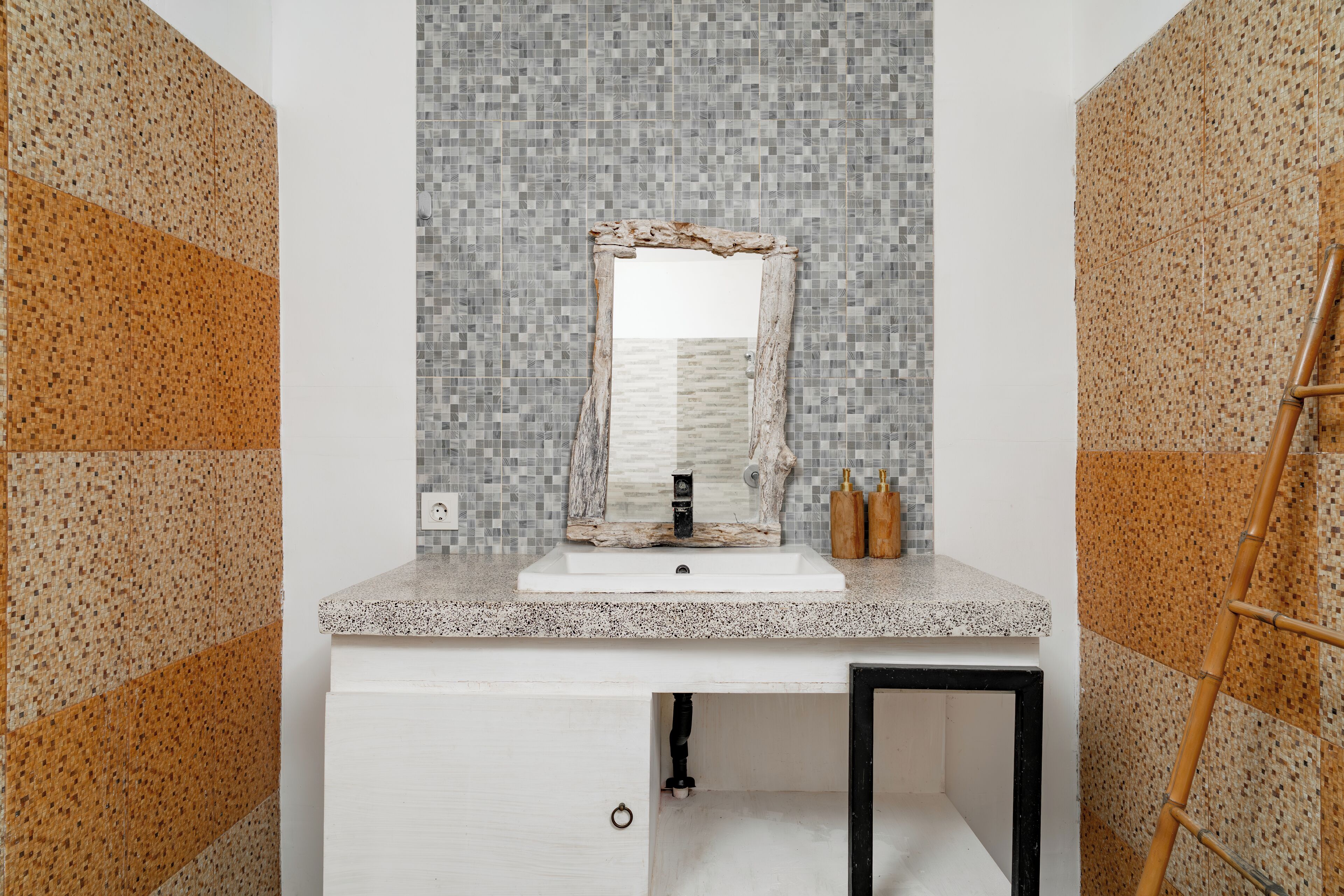 Un baño con lavamanos blanco, espejo y salpicadero de azulejos.