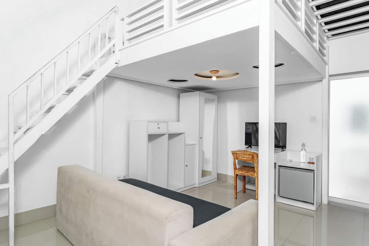 Una habitación moderna y minimalista con una escalera blanca, un sofá, una mesita y una pequeña cocina.