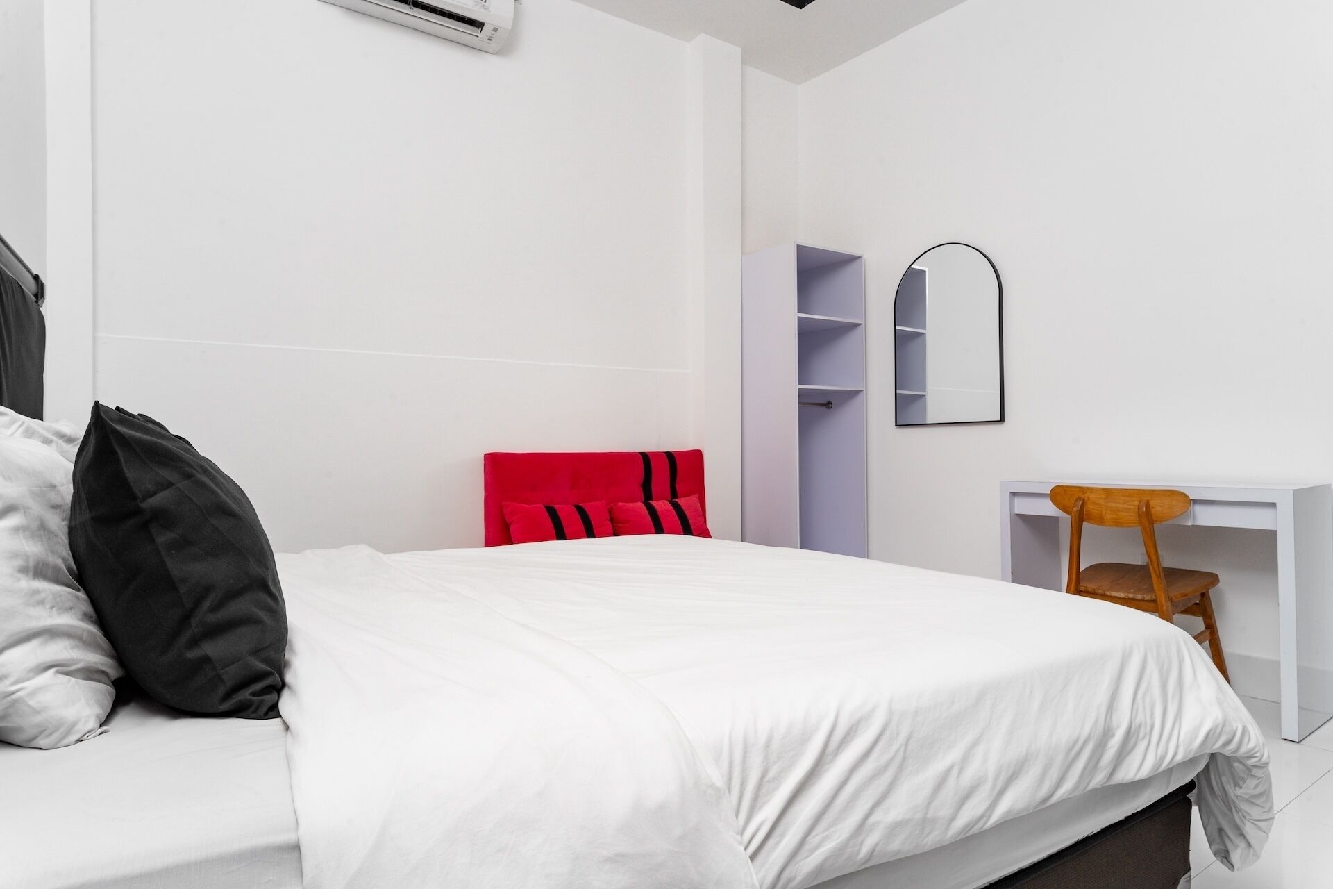 Een moderne hotelkamer met een groot bed, een bureau met stoel, een kledingkast en een spiegel.