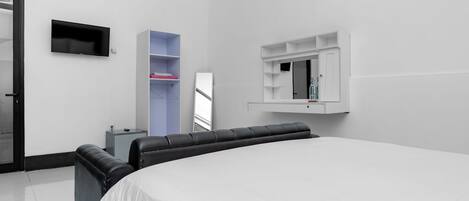 A modern hotel room with a large bed, a flat-screen TV mounted on the wall, a built-in wardrobe, and a small bedside table.