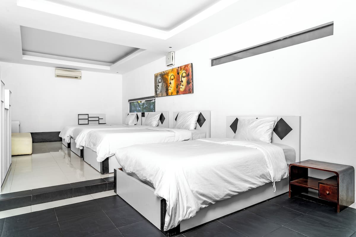 Una habitación de hotel moderna con dos camas, una mesita de madera y un cuadro en la pared.