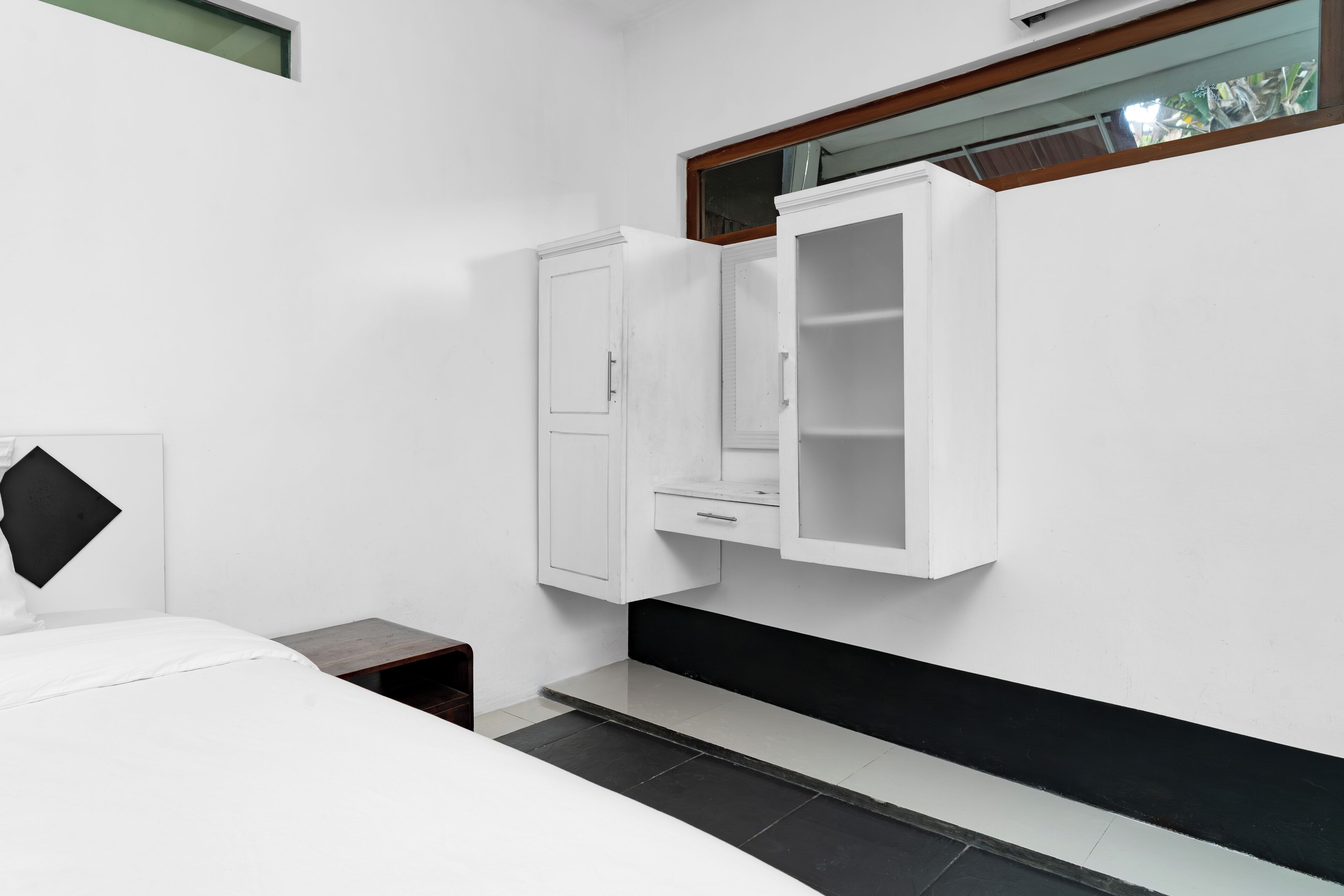 Une chambre à coucher avec un lit, une table de chevet, une armoire et une fenêtre.
