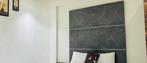 A modern bedroom with a large bed, a ceiling fan, and a dark accent wall.
