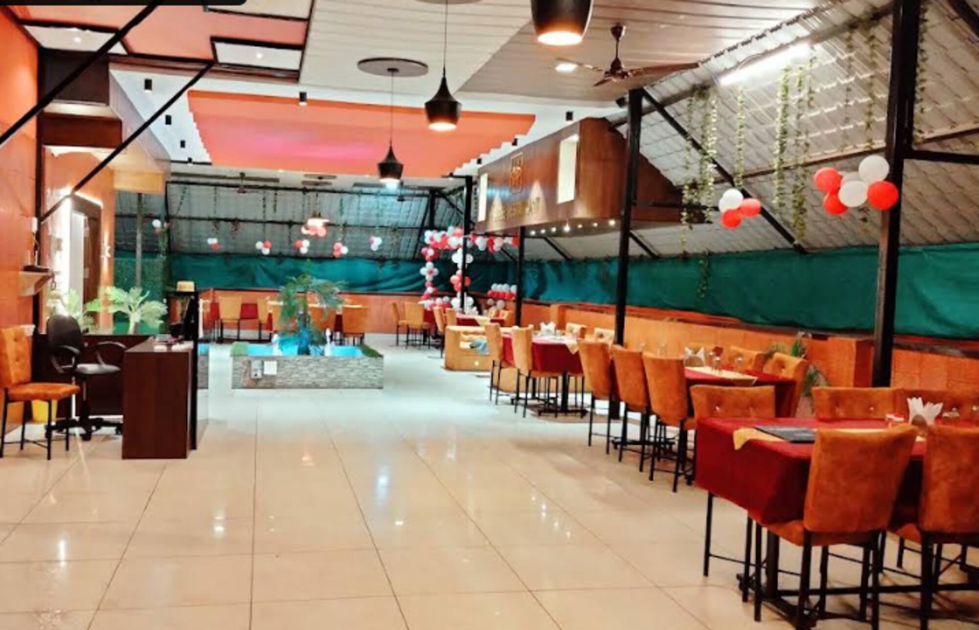 A spacious indoor venue with multiple seating areas, a central decorative fountain, and a stage with a backdrop.