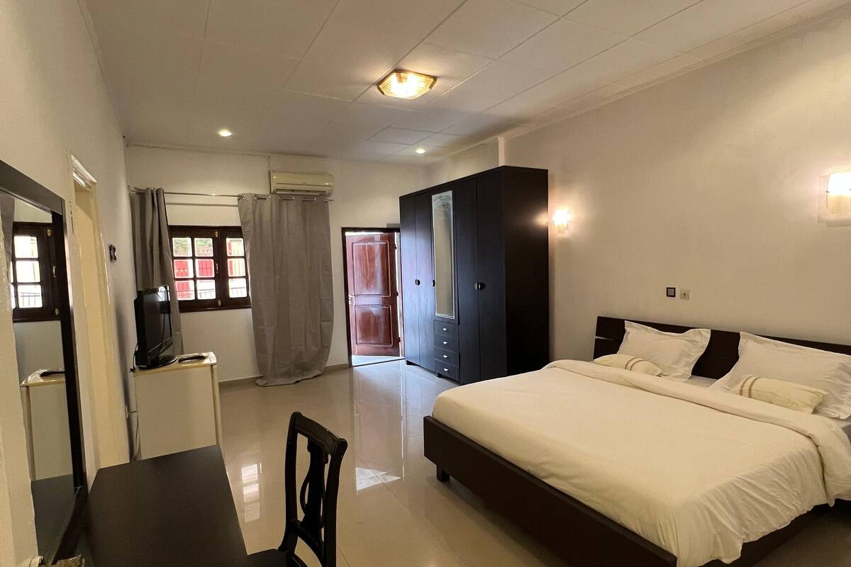 A hotel room with a bed, a desk, a wardrobe, and a television.