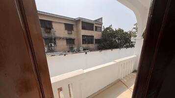 A balcony with a white railing, a tiled floor, and a view of buildings in the background.