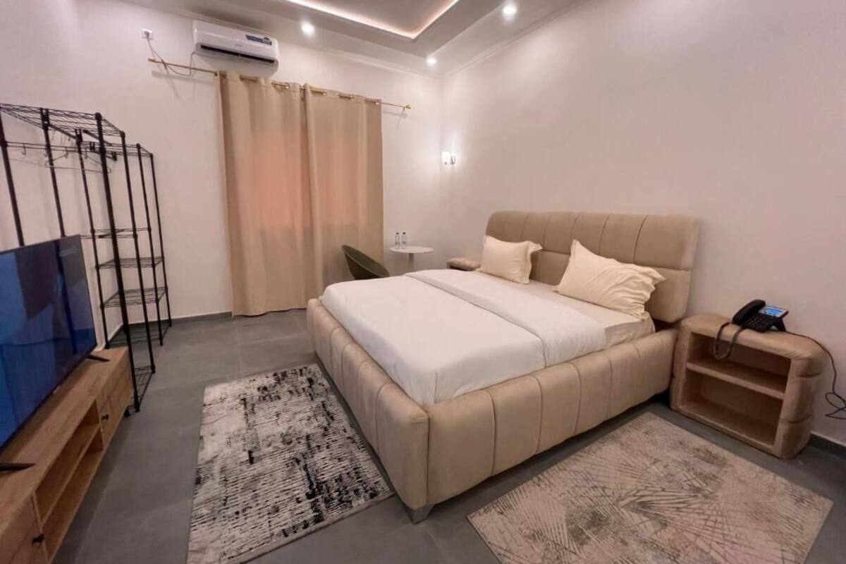A modern bedroom with a bed, a TV, a desk, and a chair.