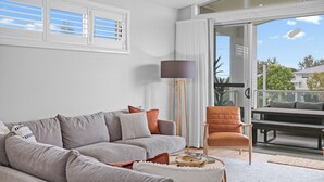 Un salon moderne avec un canapé gris, une lampe sur pied et un coin repas comprenant une table et des chaises.