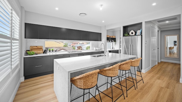 Une cuisine moderne dotée d’un îlot central, de tabourets de bar et offrant une vue sur le quartier.