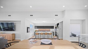 Une cuisine moderne avec un îlot central, un coin repas doté d’une table en bois et un salon avec un canapé.