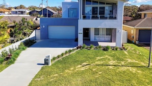 Une maison moderne à deux étages, dotée d’un grand garage, d’une allée couverte et d’une pelouse bien entretenue.