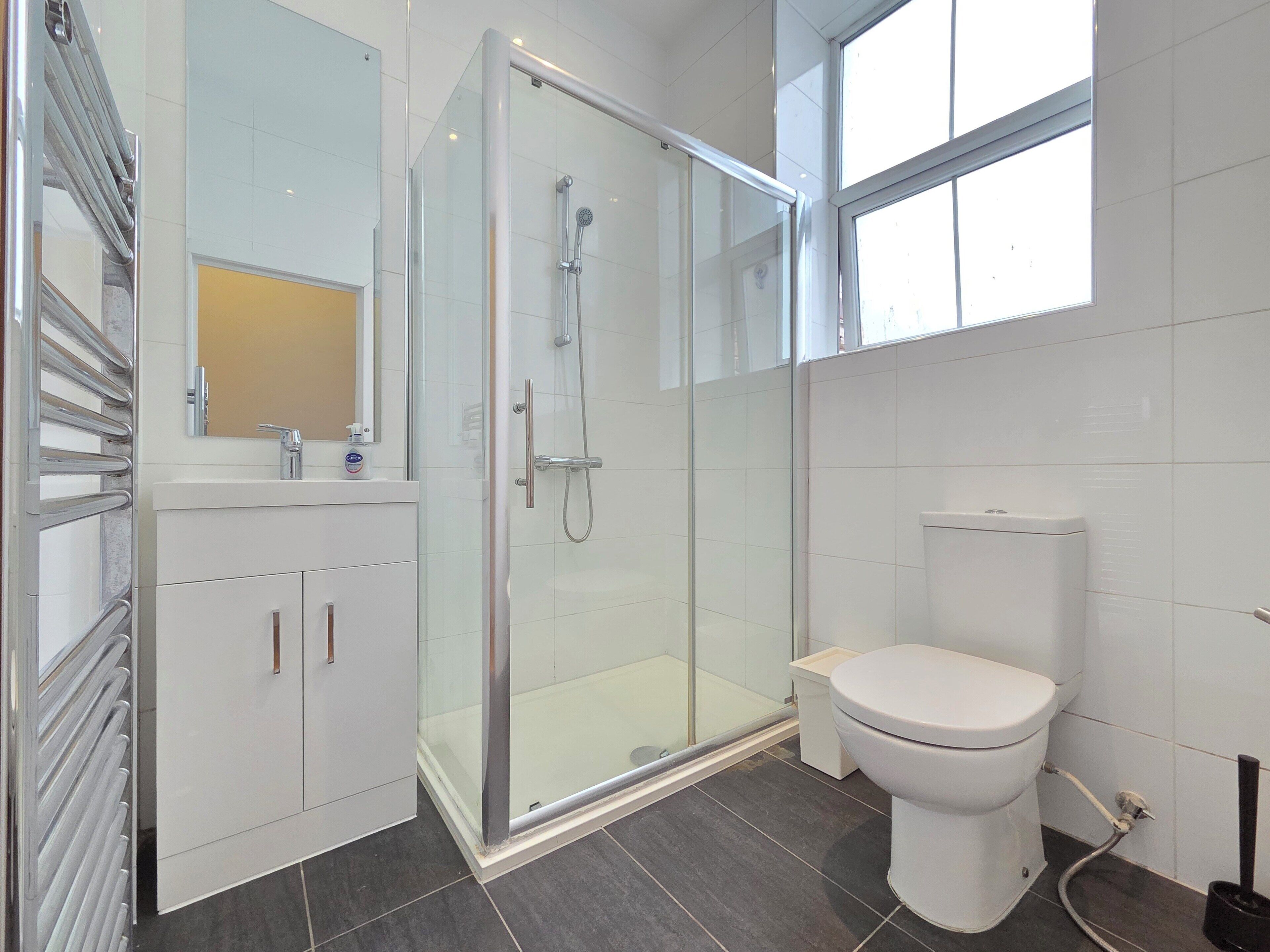 A modern bathroom with a glass-enclosed shower, a white toilet, and a vanity with a mirror.