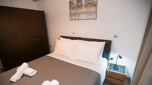 Una cama bien hecha con sábanas blancas, un cabecero de madera y una mesita de noche con lámpara.