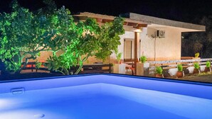 Área de piscina en la azotea con vistas a un edificio y follaje circundante.
