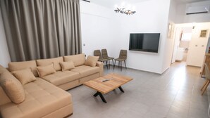 Una sala moderna con un sofá color beige, una mesa de centro de madera y dos sillones.