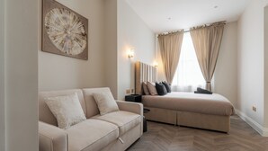 A modern bedroom with a bed, a sofa, a wall-mounted artwork, and a window with curtains.