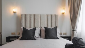A neatly made bed with a headboard, two bedside tables, and a nightstand.