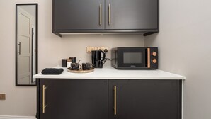 A kitchenette with a microwave, coffee maker, and storage cabinets.