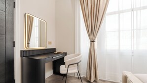 A modern bathroom with a dark vanity, a mirror, and a chair.