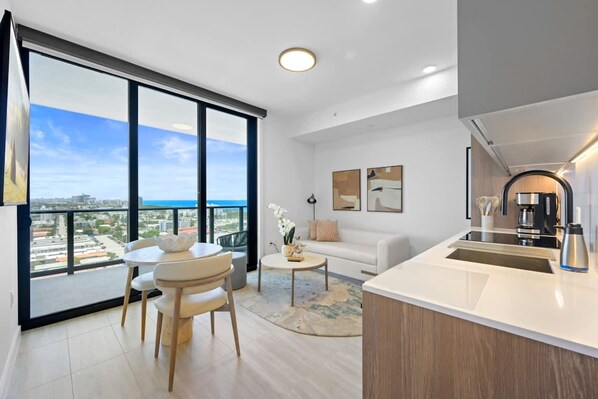 Um apartamento moderno com varanda, área de refeições, sala de estar e cozinha.