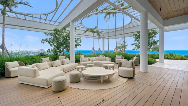 A covered outdoor seating area with a wooden deck, white furniture, and a view of the ocean. - NOK Amazing 1 BR in Miami Beach (Miami Beach)