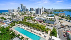 Ein Resort mit großem Pool, Palmen und einer Stadtansicht im Hintergrund.