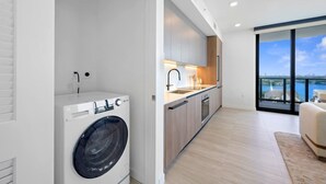 Eine moderne Wohnung mit Waschmaschine, Küche und einem Balkon mit Blick.