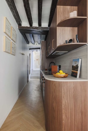 A narrow hallway with wooden cabinets and a wooden floor.