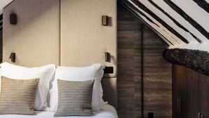 Un dormitorio con techo inclinado, cama con ropa blanca y armarios de madera.