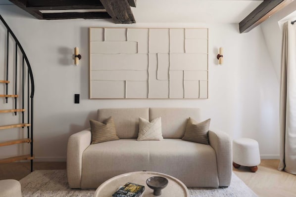 A modern living room with a sofa, a coffee table, and a large abstract wall art piece.